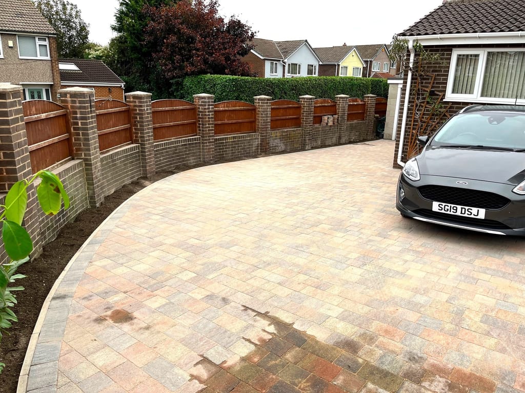 Sweeping block paved driveway with a new brick pier and panel boundary wall