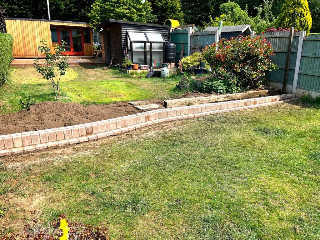 Low brick retaining edge holding a lawn back from a border and greenhouse