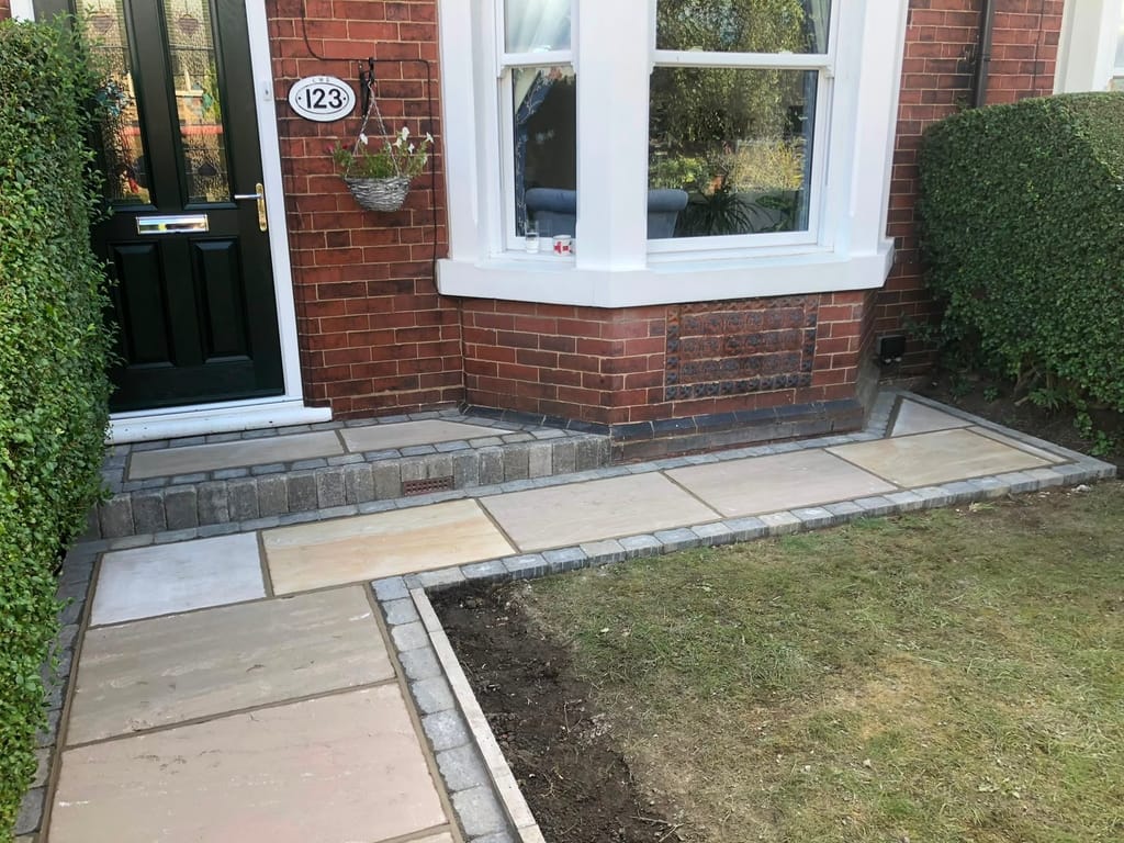 Sandstone front path and doorstep with sett borders at a red brick house with a sash bay window